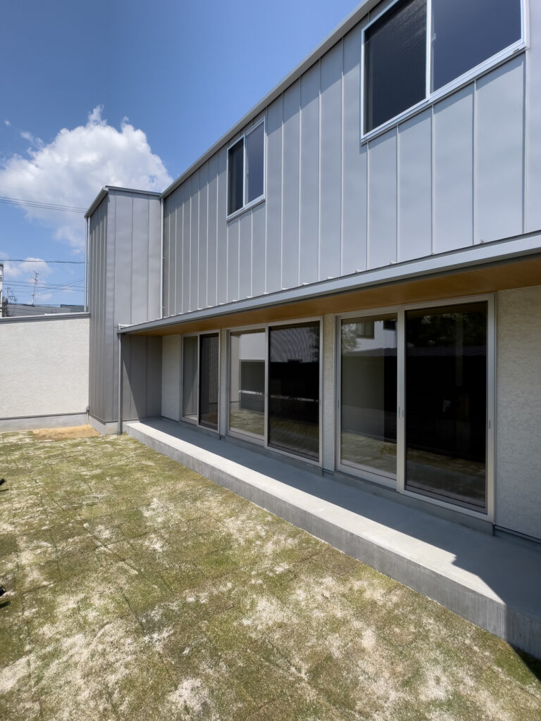 岐阜県神戸町に建つ木造二階建て注文住宅。 シルバー色のガルバリウム鋼板の外壁と、板張りの軒天井がコントラストをつくる。